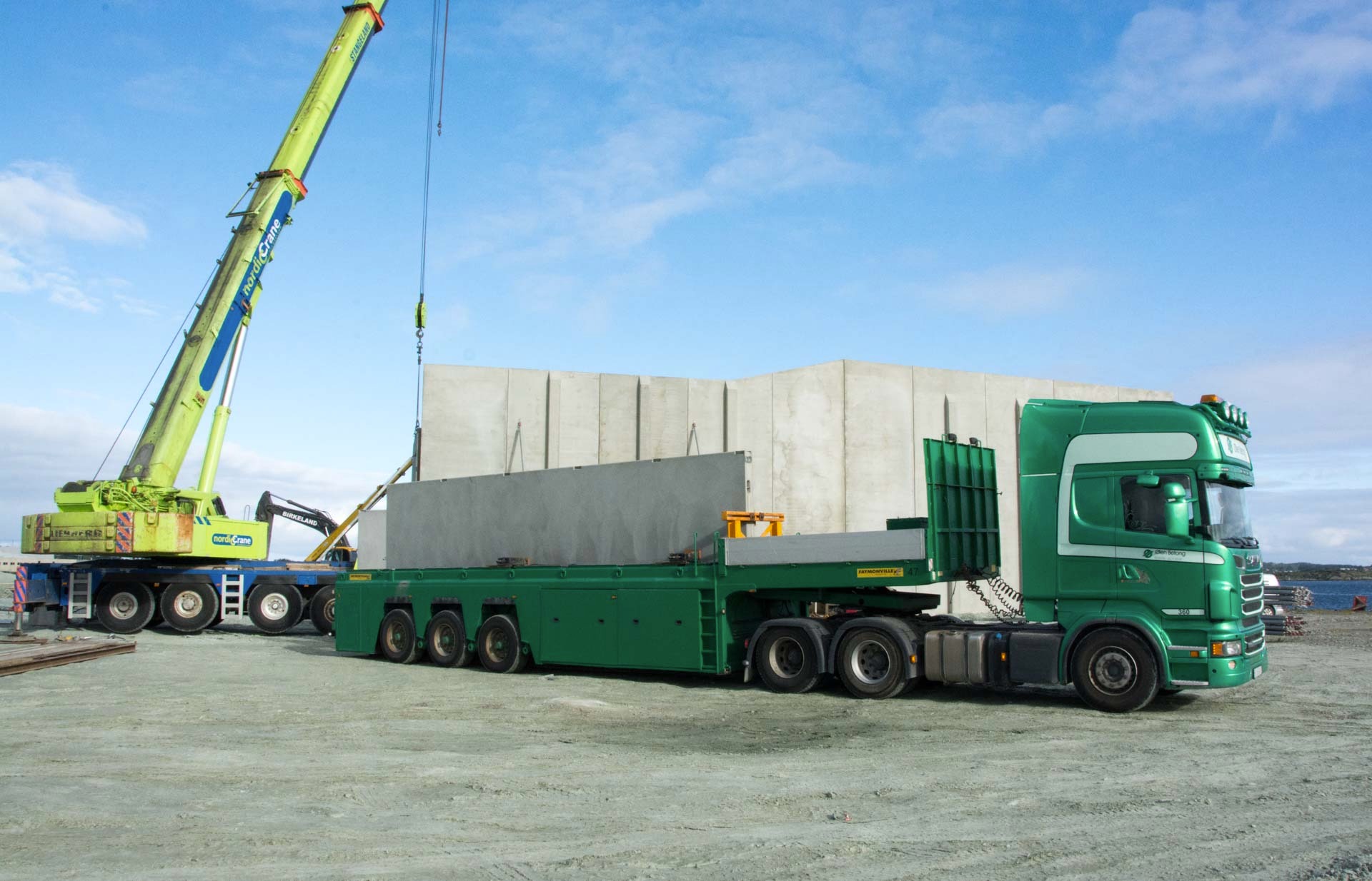 En kranbil laster byggelementer på en semi med spesialbygd tilhenger